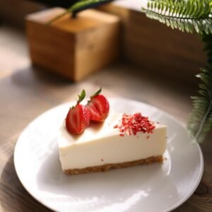 A slice of creamy cheesecake topped with fresh strawberries, perfect for dessert lovers.
