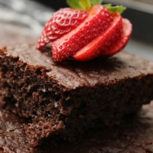 Close-up of a rich chocolate brownie topped with fresh sliced strawberry.