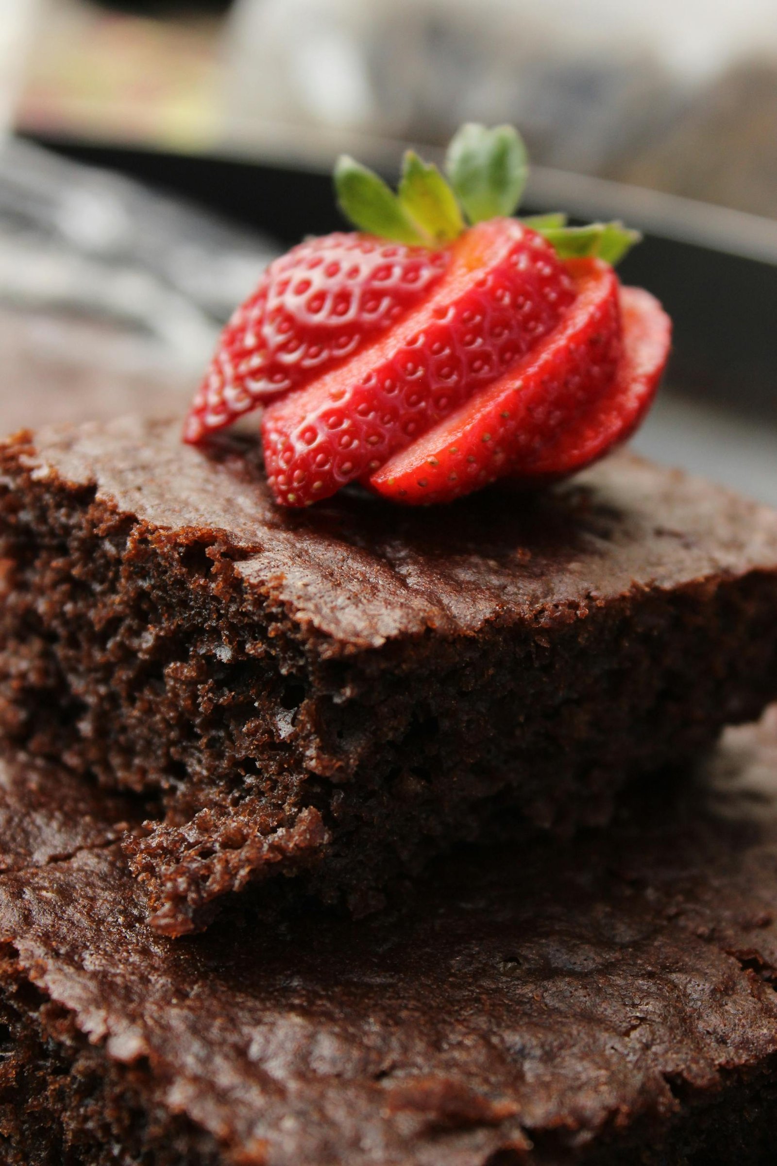 Close-up of a rich chocolate brownie topped with fresh sliced strawberry.